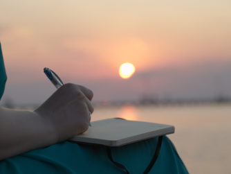 Woman writing in her diary at sunset