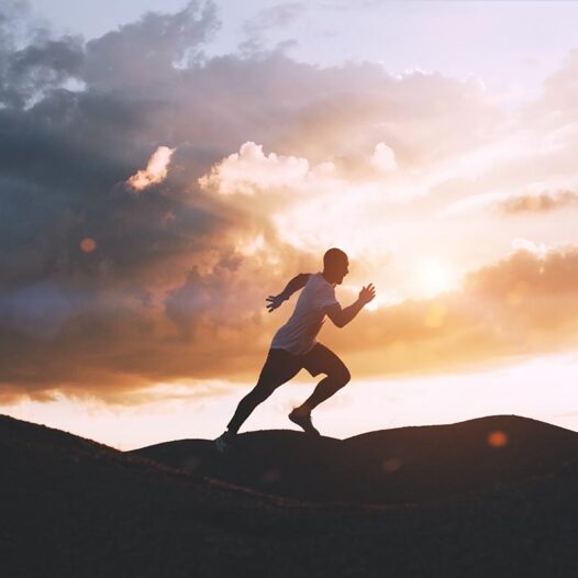Athlete runs quickly through the hills outdoors at sunset. healthy lifestyle concept